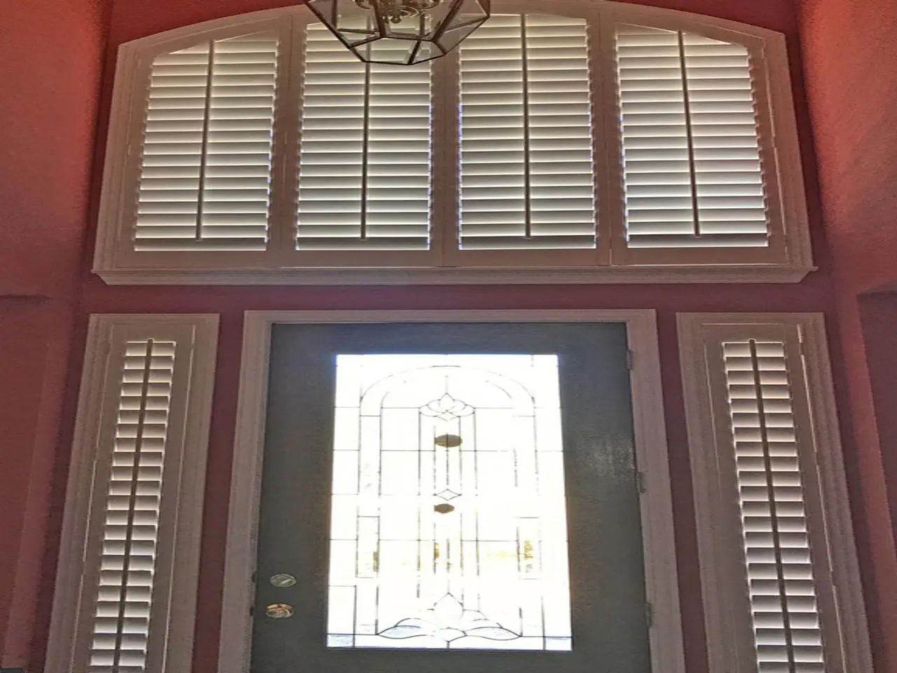 Two story foyer with interior shutters on the sidelights and arched window over the door