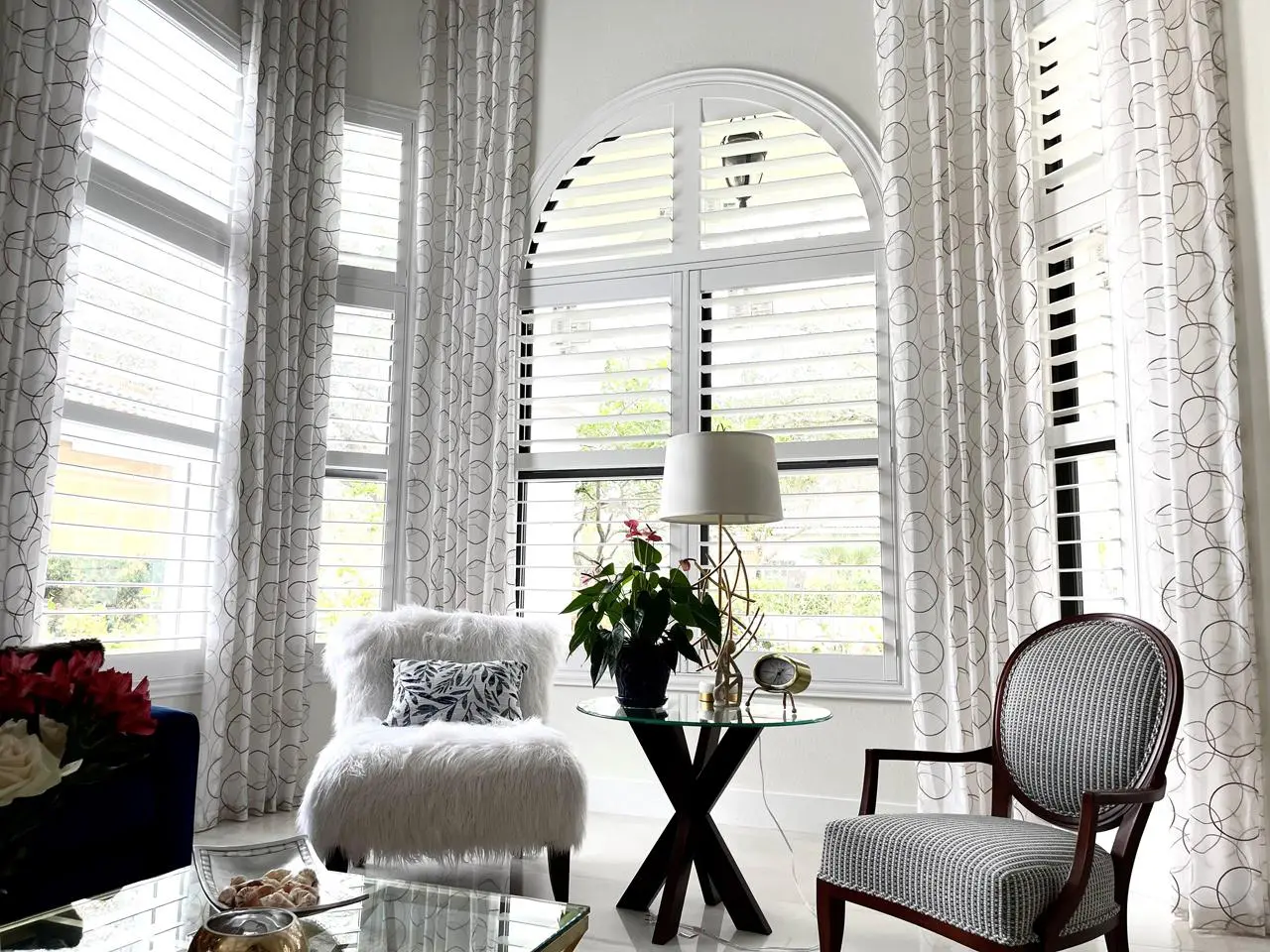 Arched window with shutters and drapes in living room