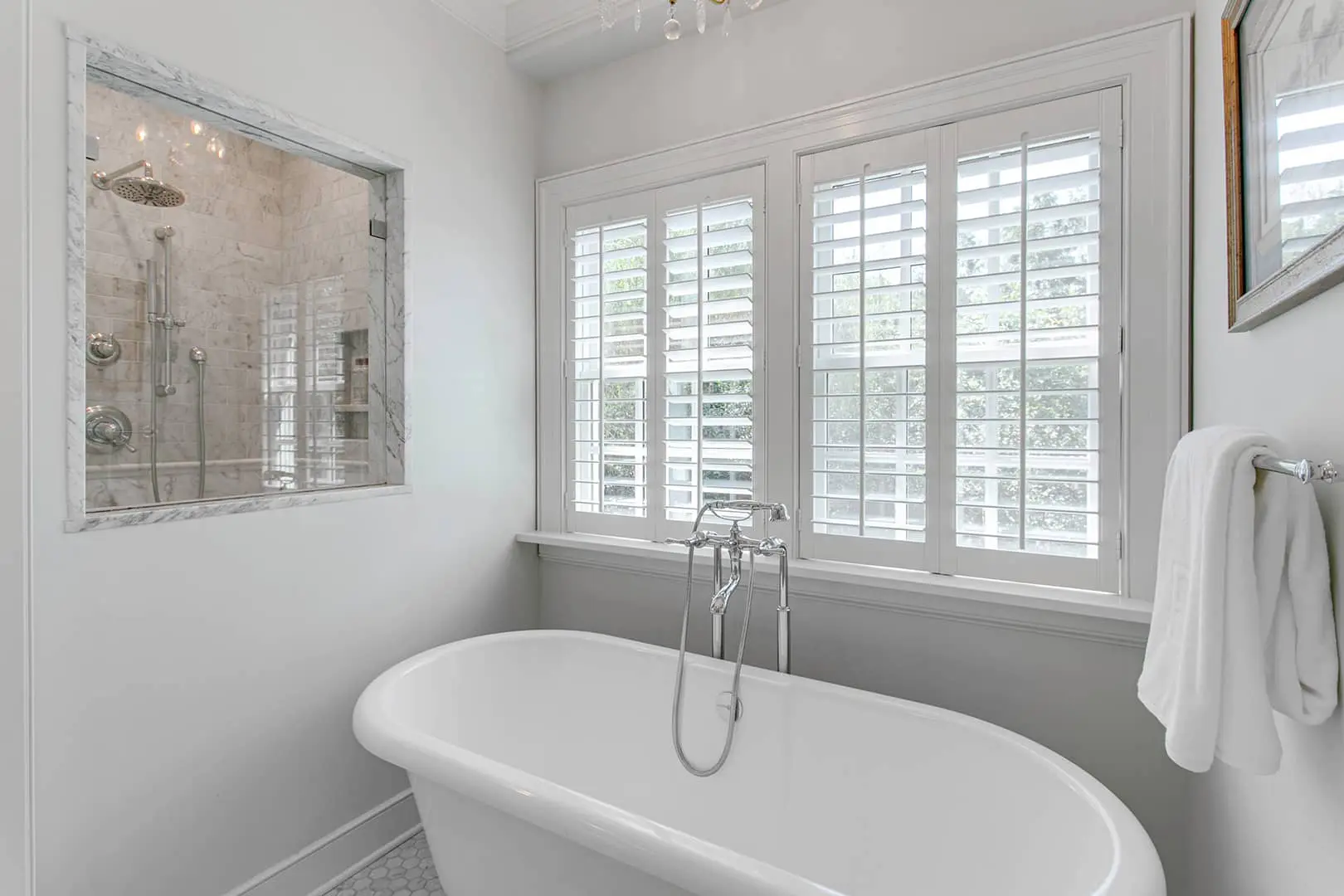 plantation shutters on 2 windows above the tub
