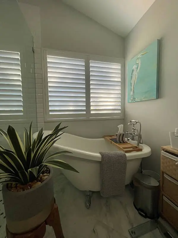 tall, arched windows with white plantation shutters in a bathroom