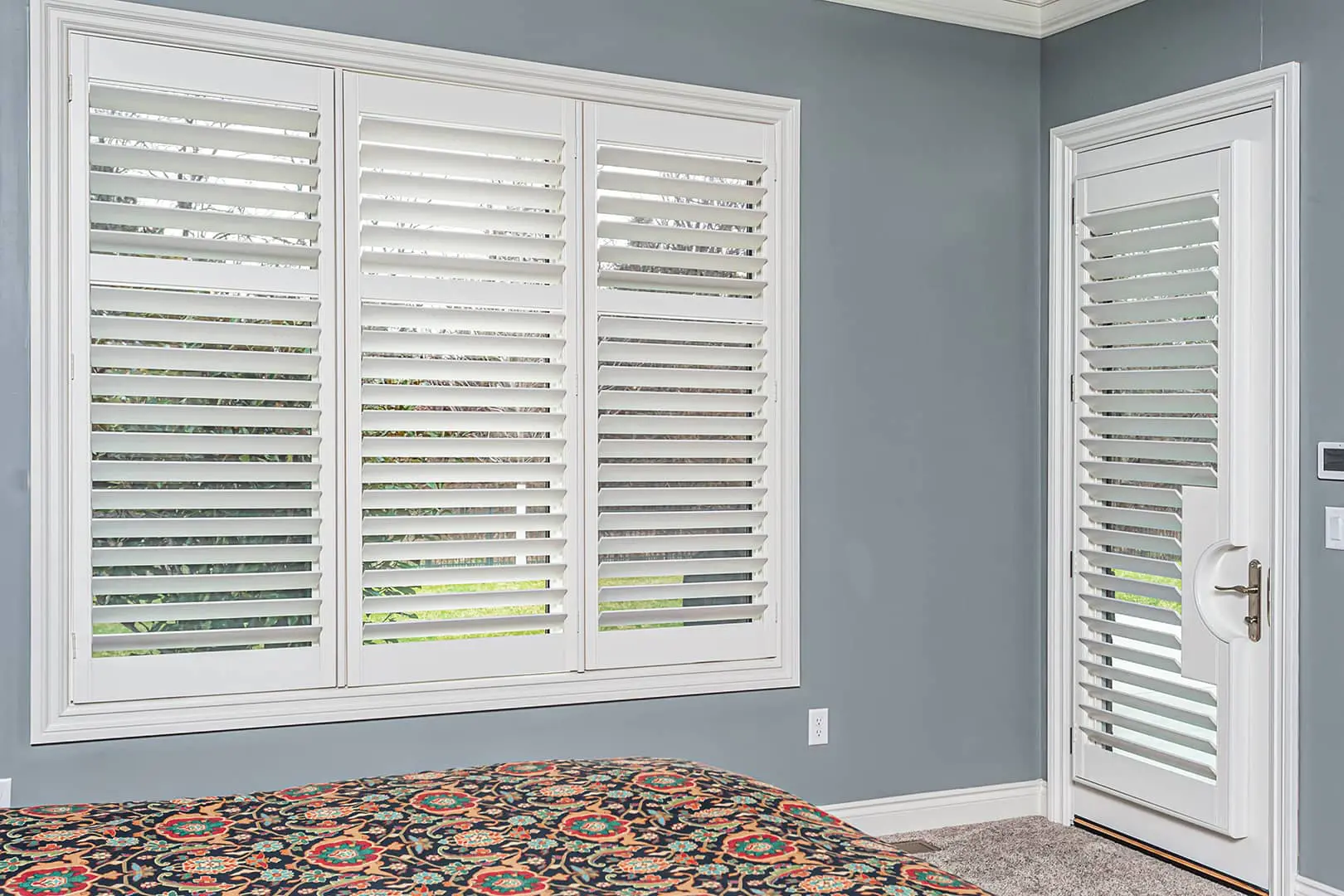 white plantation shutters on bedroom window and door