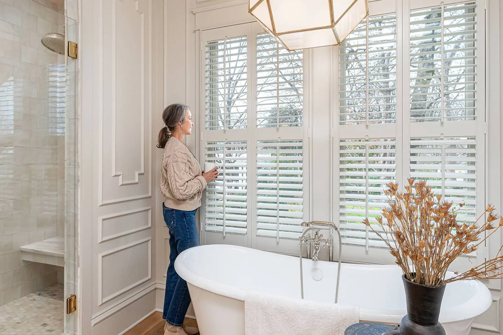 woman by large window covered with plantation shutters