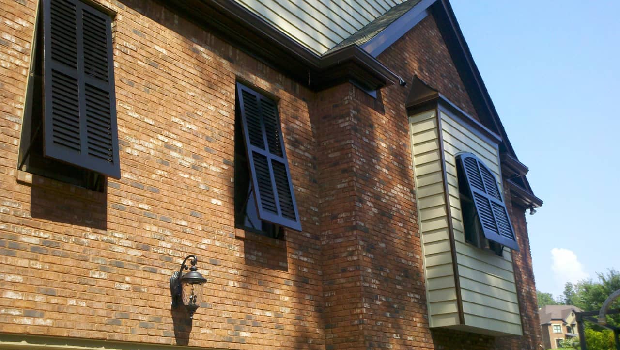 Bahama shutters on brick and siding house