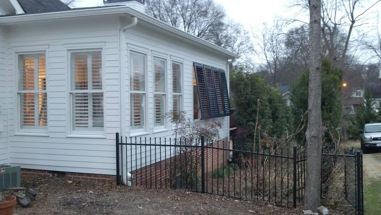 Bahama shutters outside house with plantation shutters on inside of windows