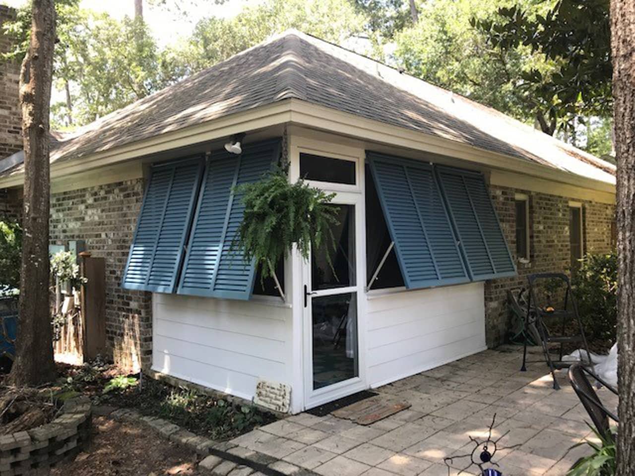 Bahama shutters on house with a patio