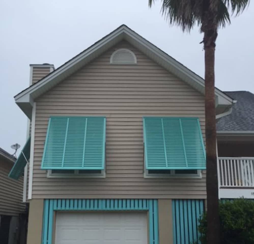 Bahama shutters on brick and siding house