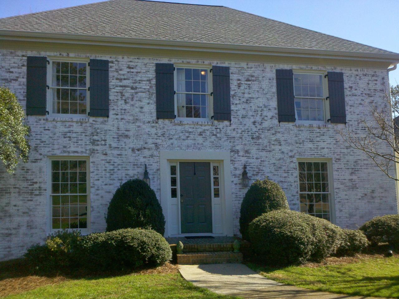 Board and batten shutters on a washed brick house