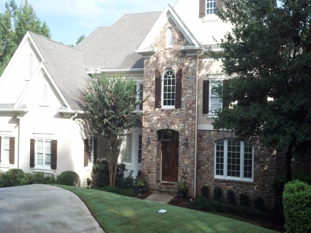 Arched and rectangular shutters on brick and stucco house