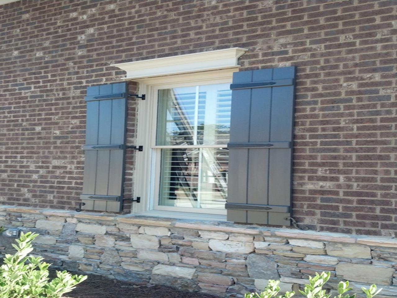 Close up view of window of brick house with board and batten shutters