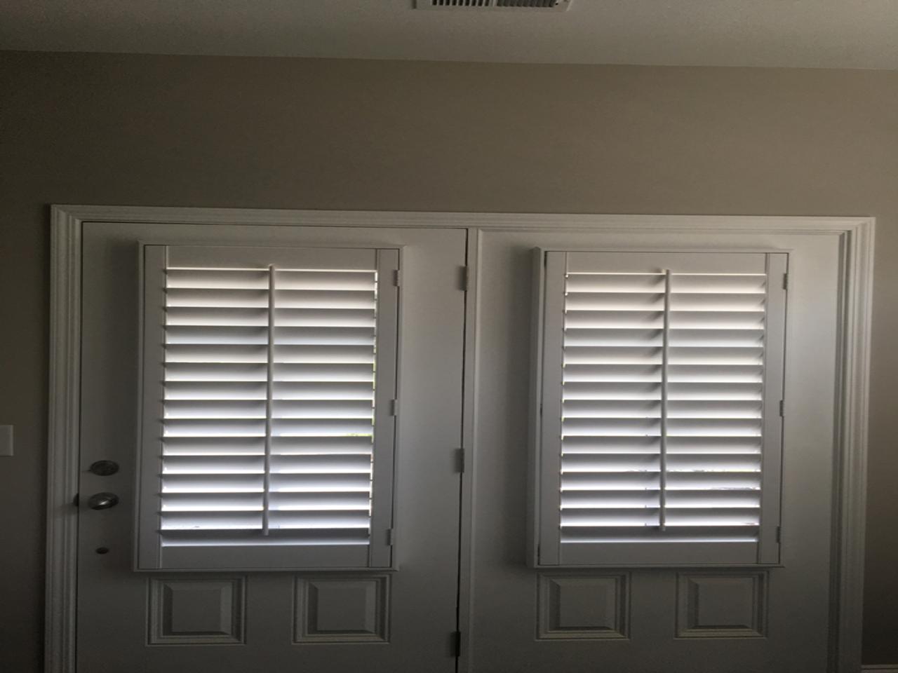 Double doors with plantation shutters on the windows on the top portions
