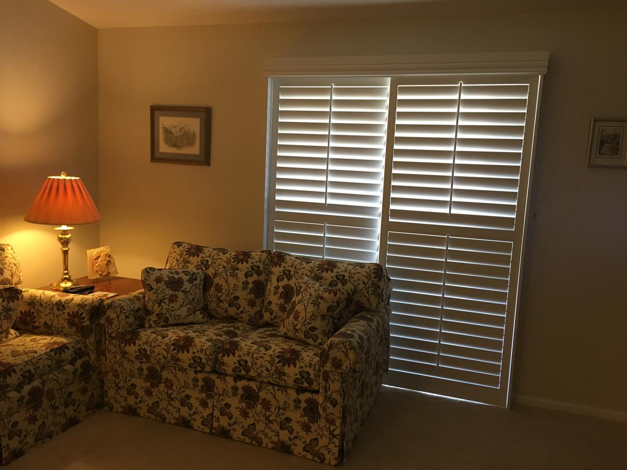 Sliding glass doors in living room with bypass shutters