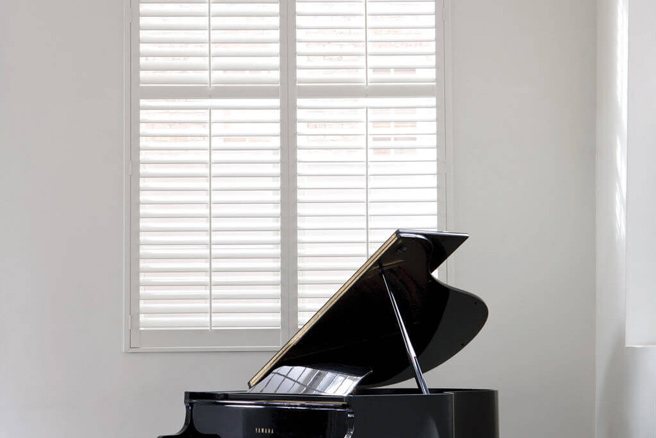 Heritage-DiningRoom-1 white plantation shutters behind a piano