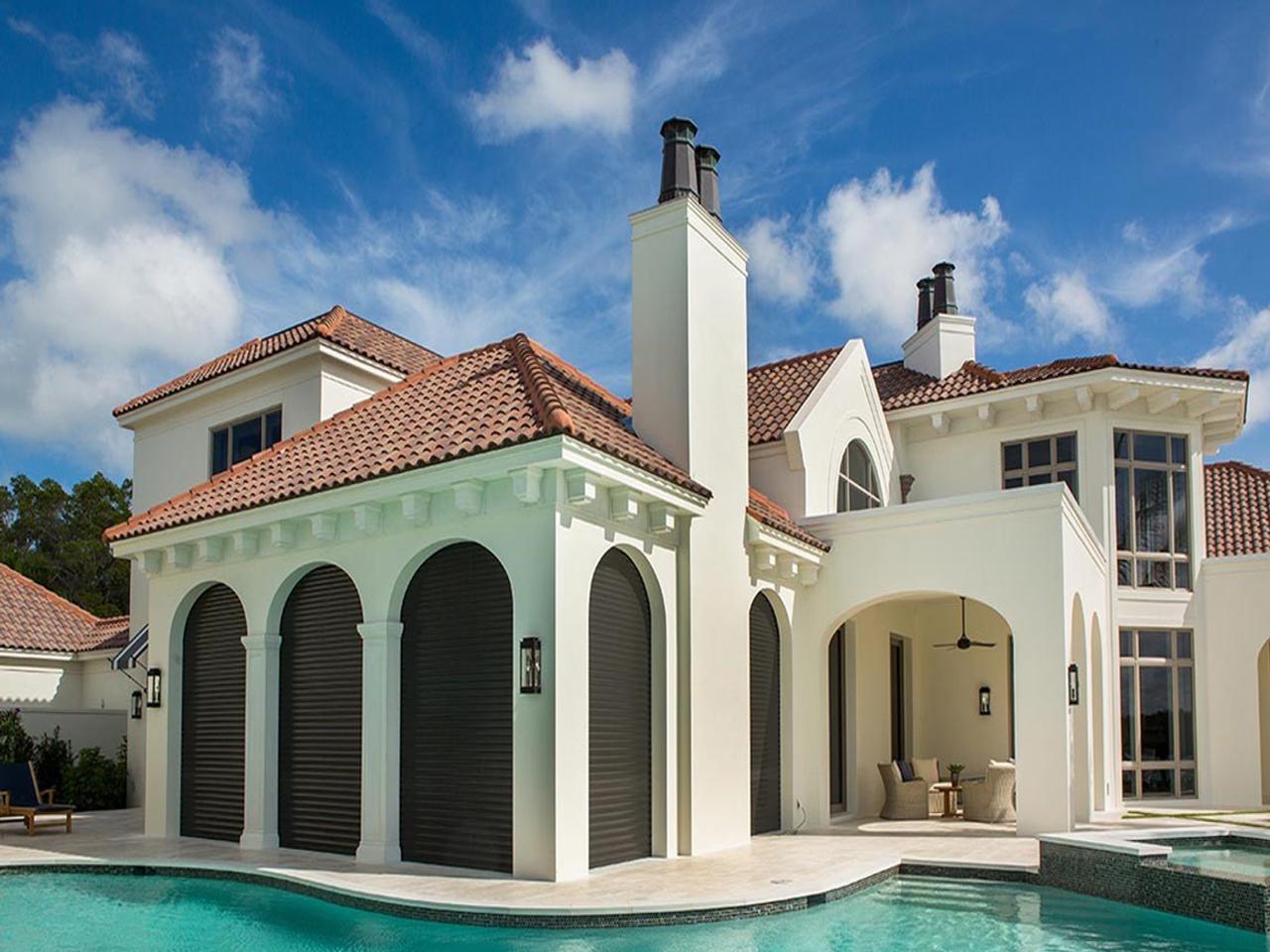 Storm shutters lowered by house with a pool