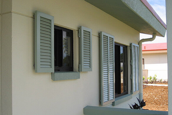 Storm shutters lowered by house with a pool