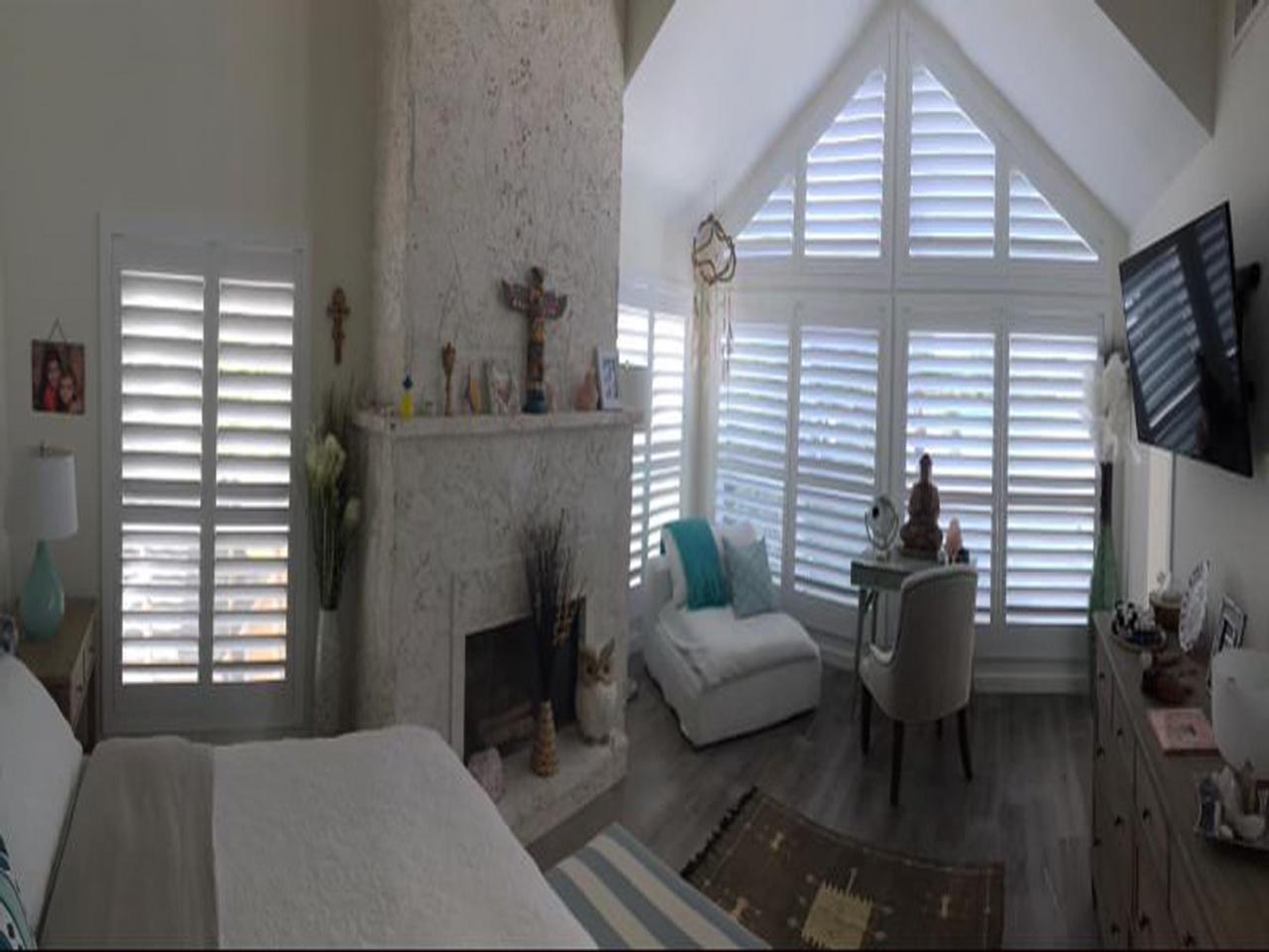 Bedroom with shutters on slant top windows