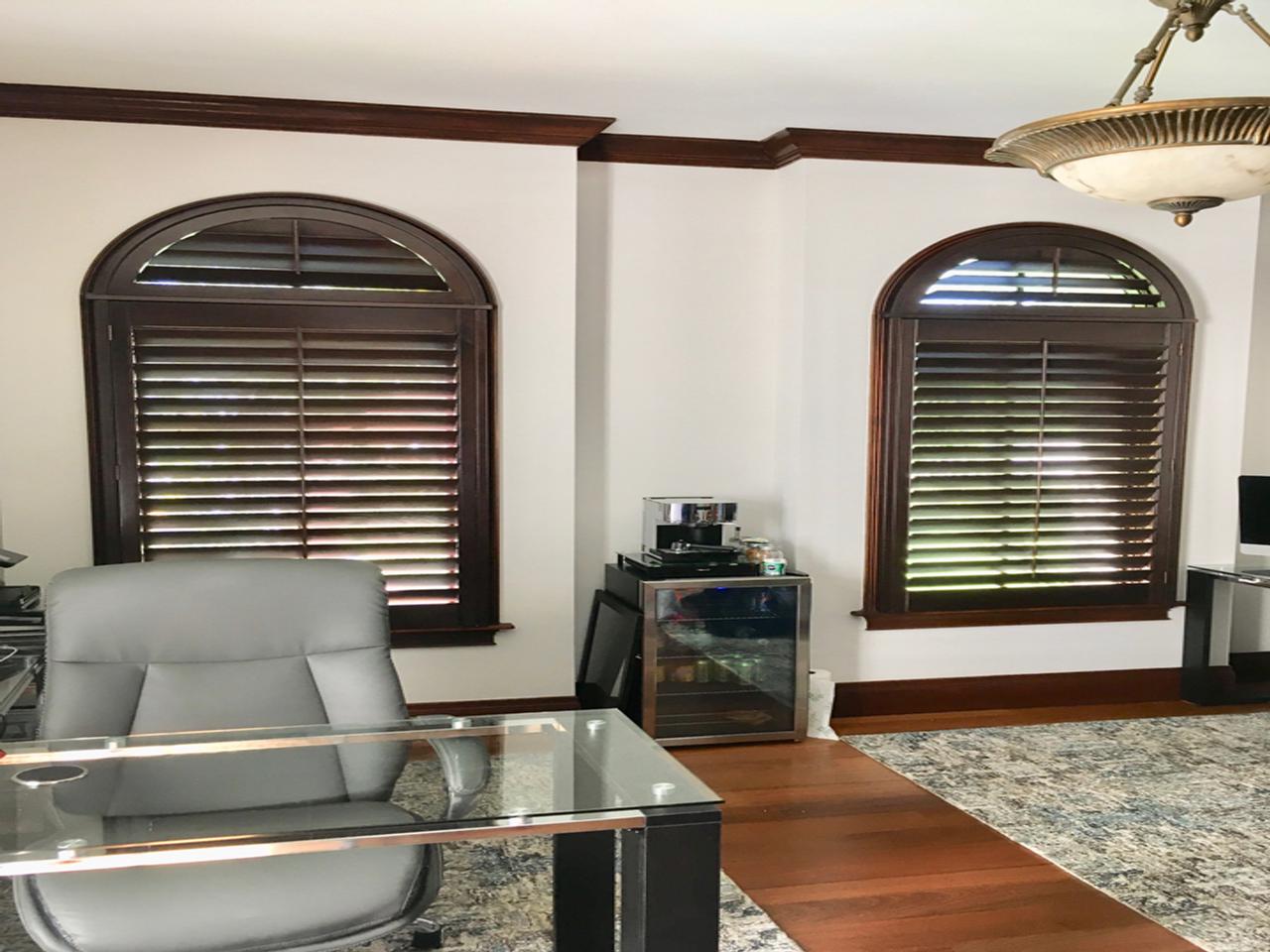 Stained shutters on arched windows in a home office
