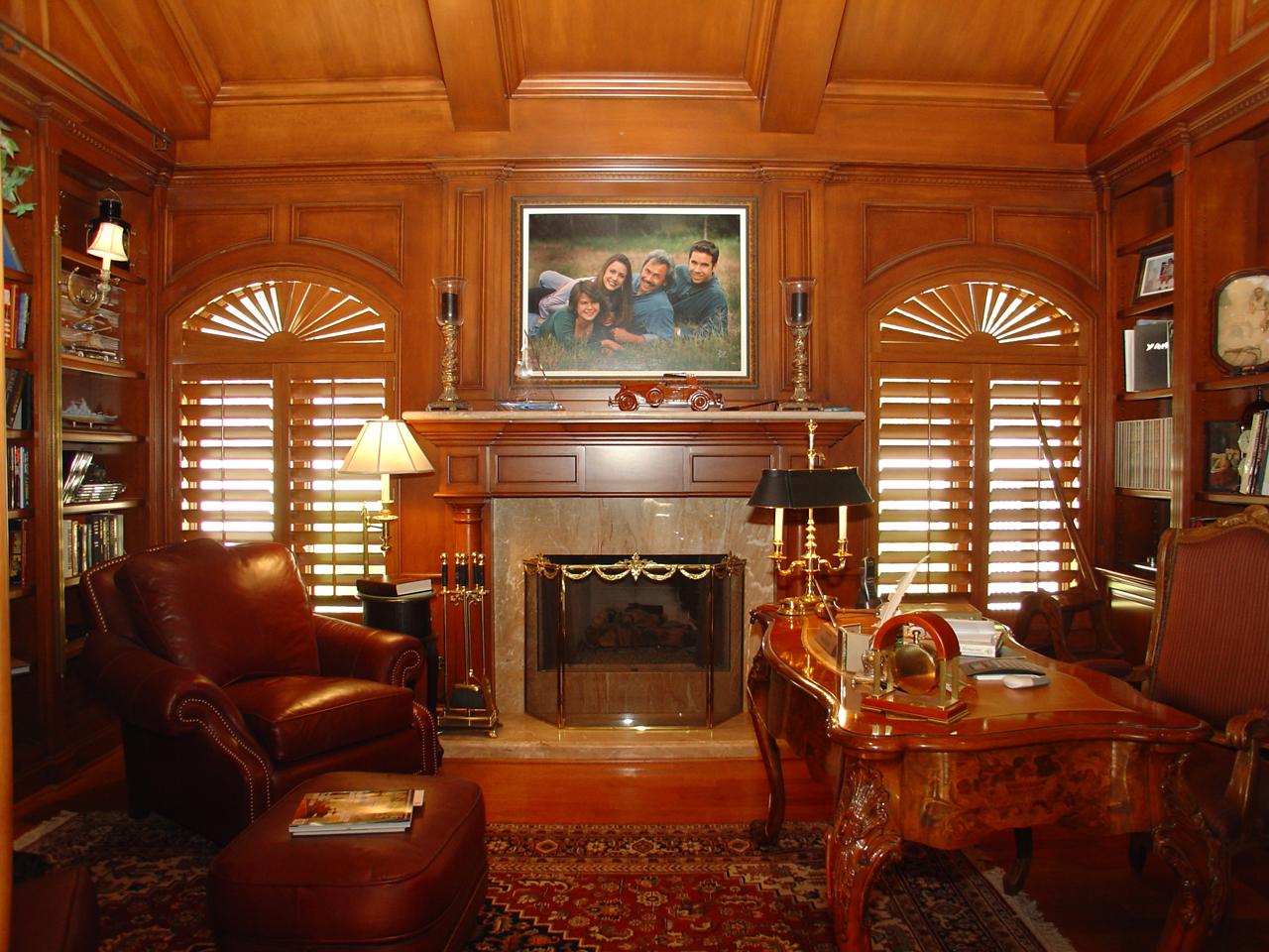 Wood paneled home office with stained shutters on arched windows