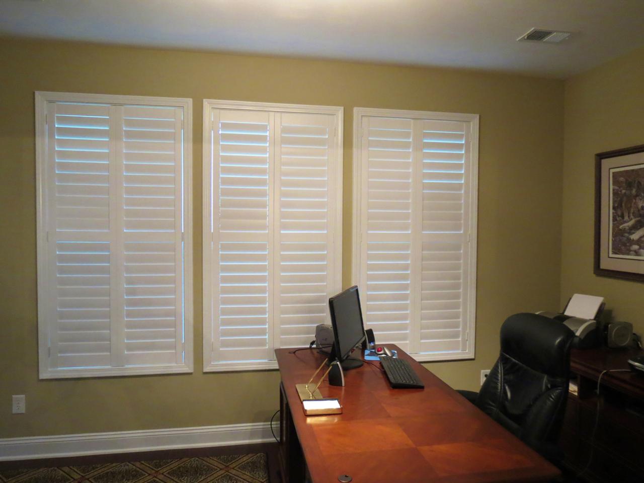 Home office with louvers closed on plantation shutters