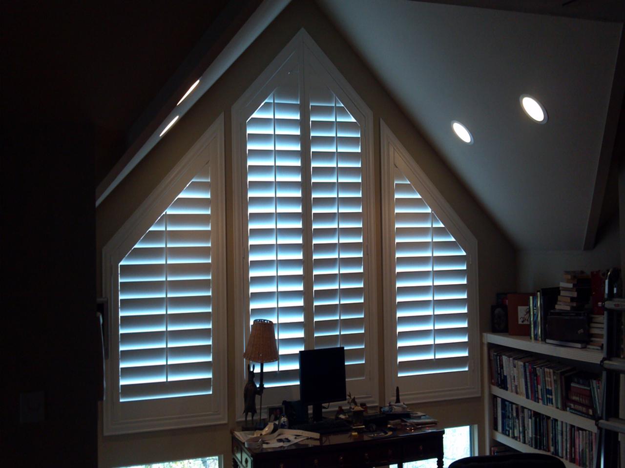 Uniquely shaped windows with custom interior shutters in a home office
