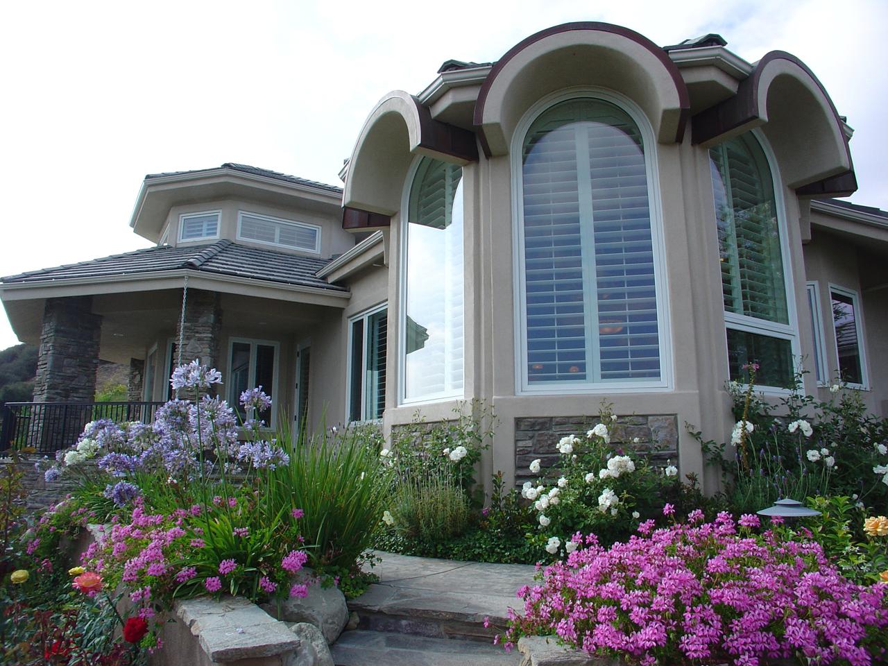 Outside view of large arched window with plantation shutters