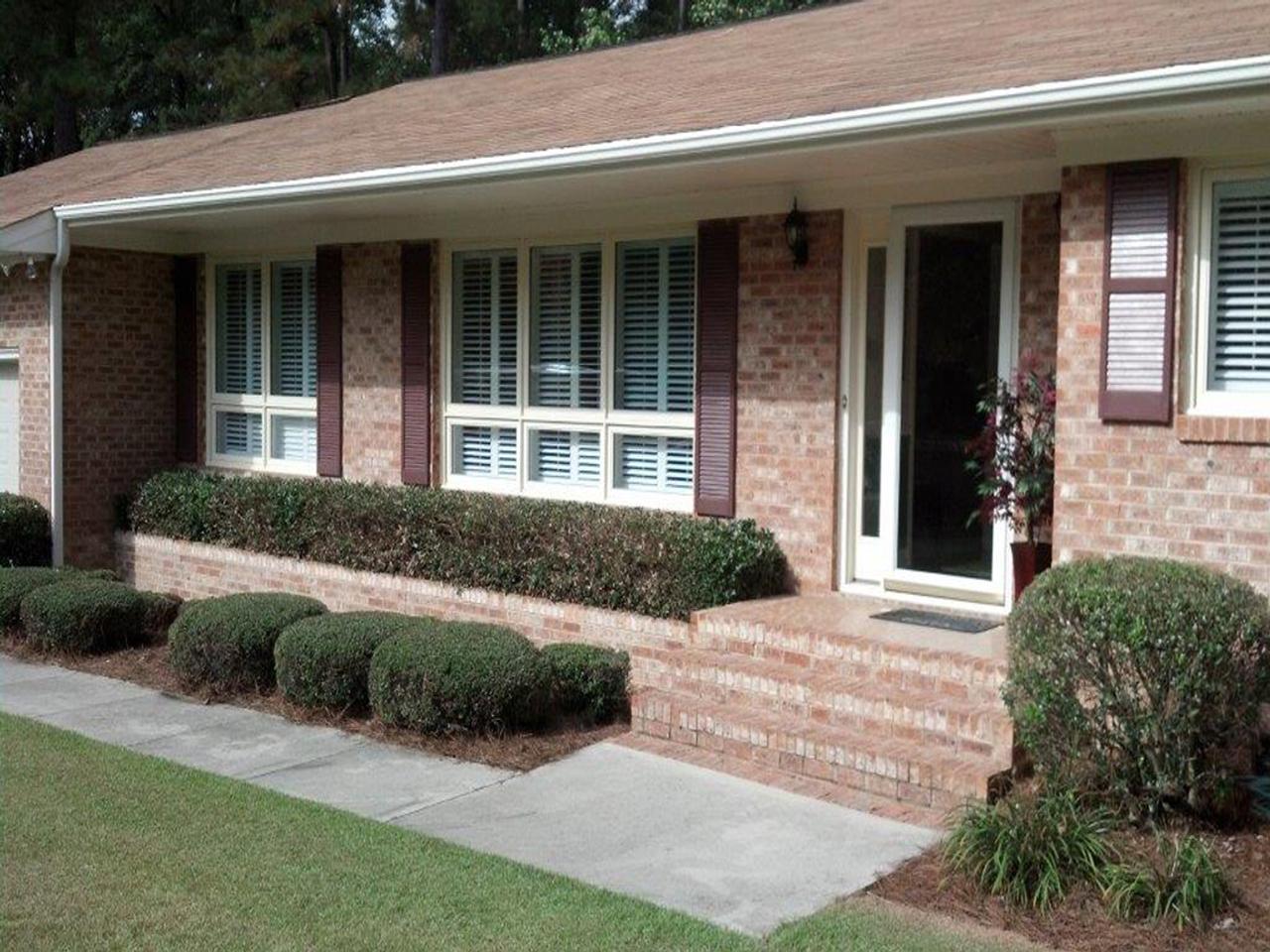 Exterior view of brick house with low divider rail and louvered exterior shutters