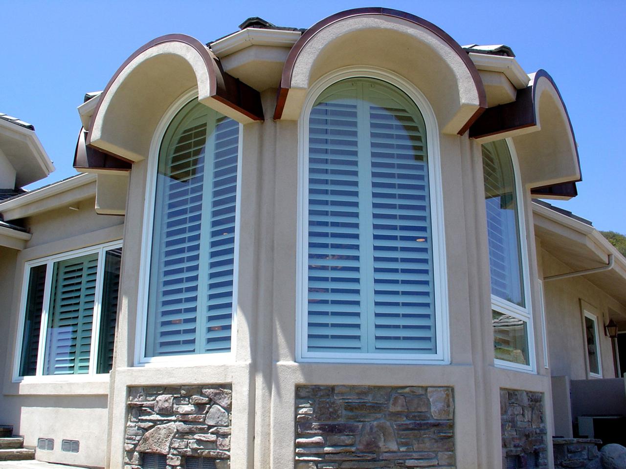 Outside view of arched windows with interior shutters