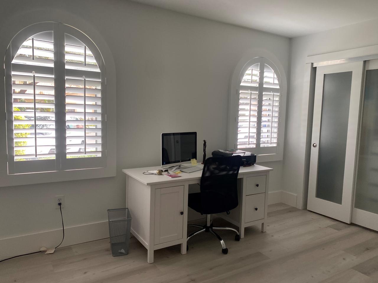 Home office with arched windows with plantation shutters