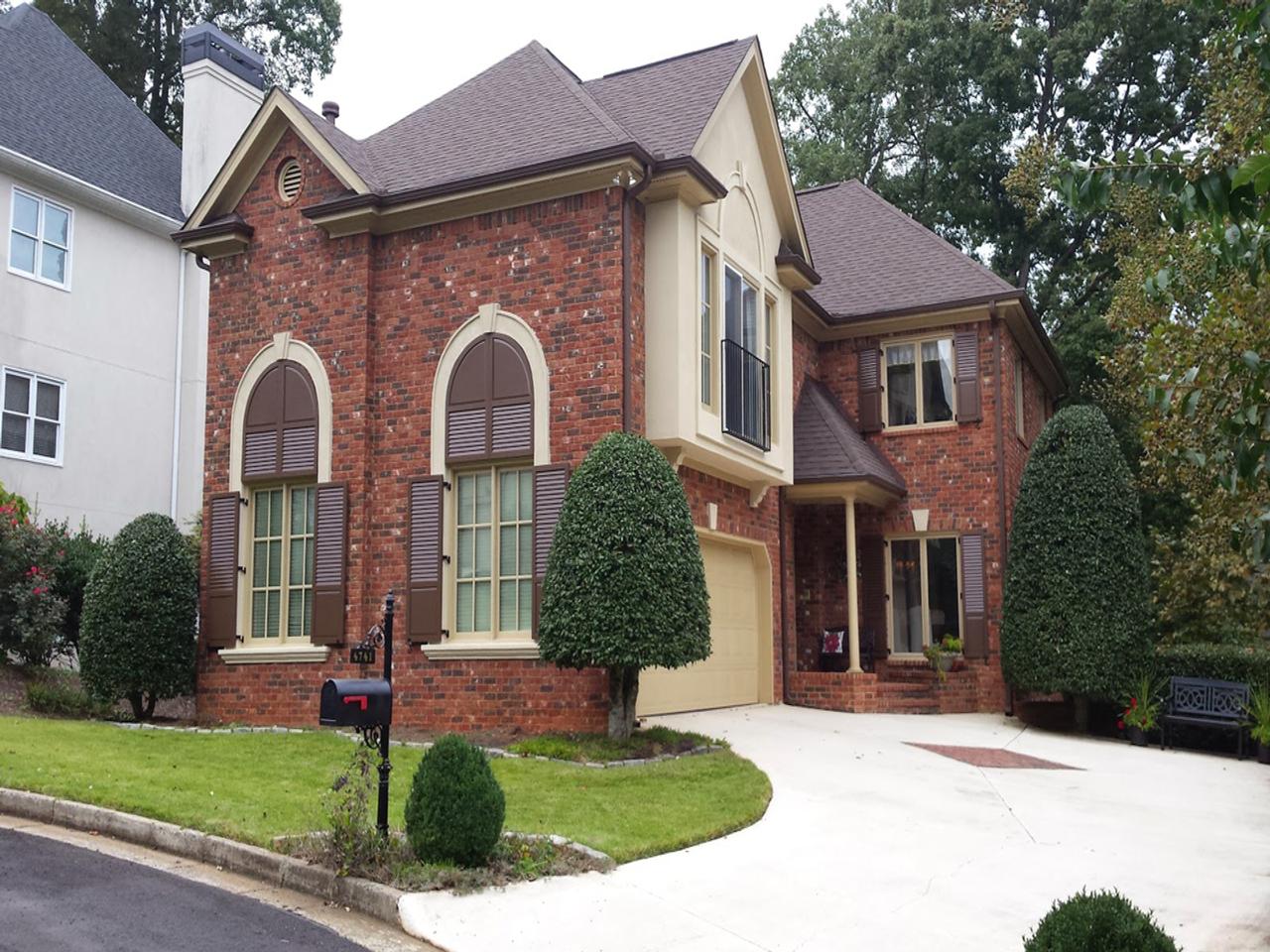 Brown combination louvered and raised panel shutters on a brick house