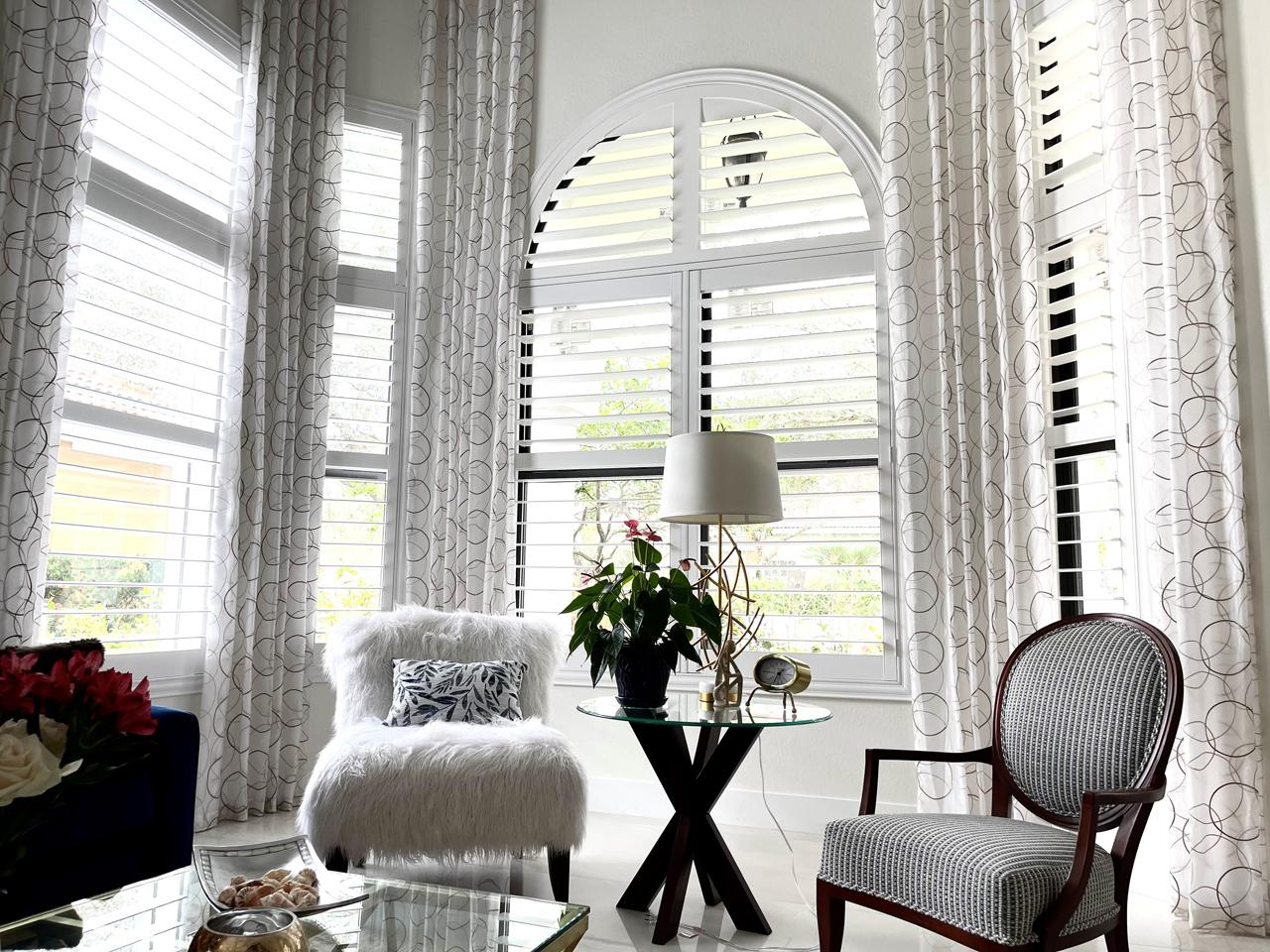 Arched window with shutters and drapes in living room