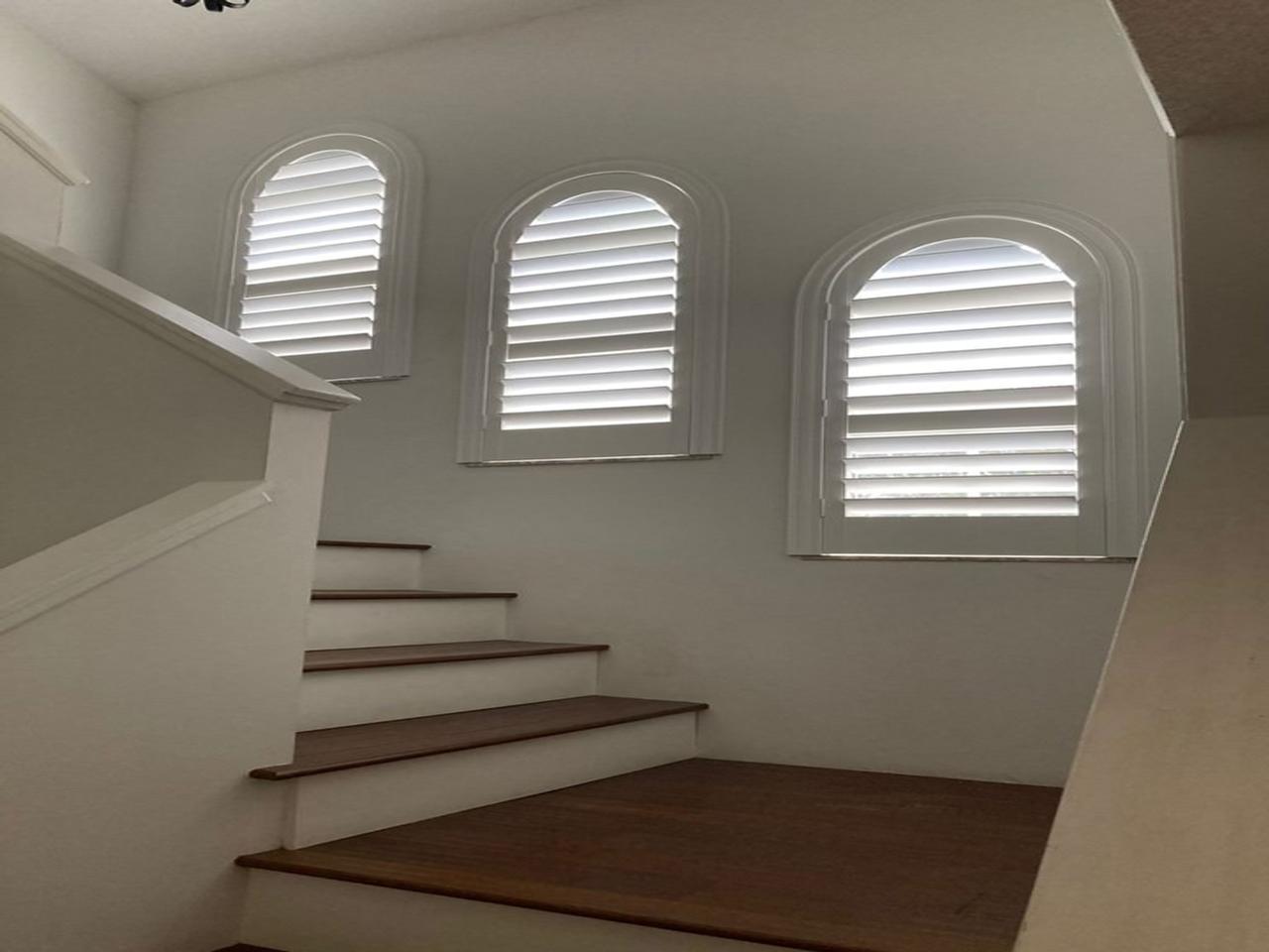 Arched windows with interior shutters in stairway