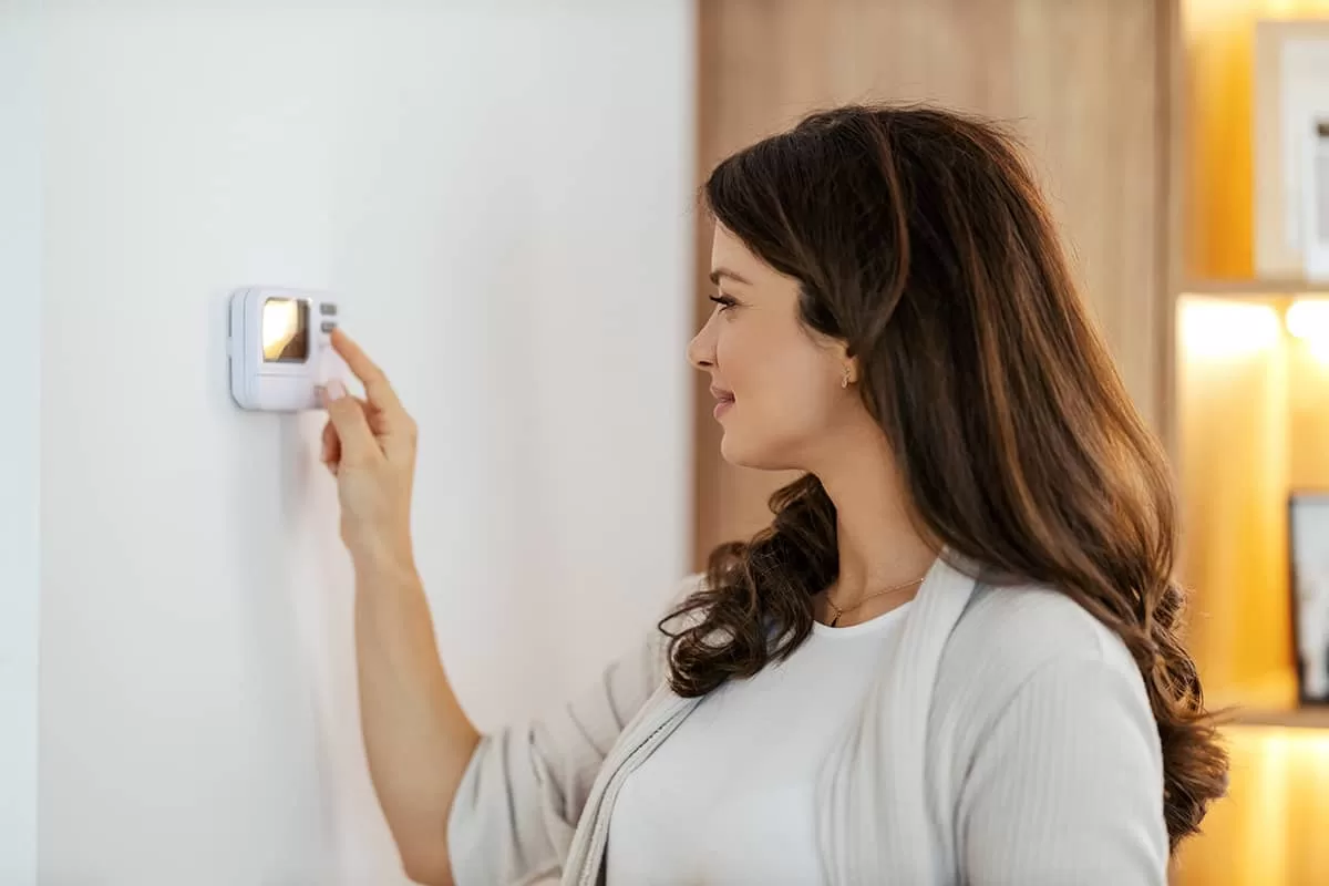 happy woman adjusting thermostat