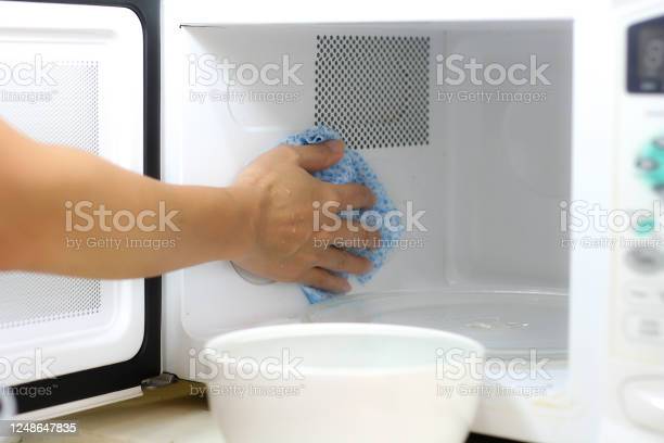 Using a cloth to clean a microwave oven in kitchen room