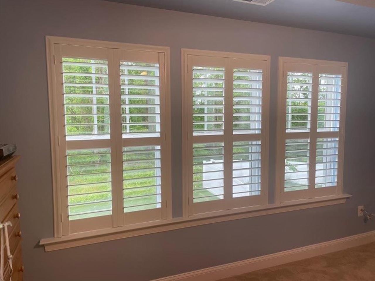 Triple windows in a bedroom with shutters